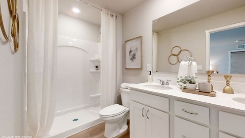 Private primary bathroom located in the primary bedroom featuring walk in shower and double sink vanity