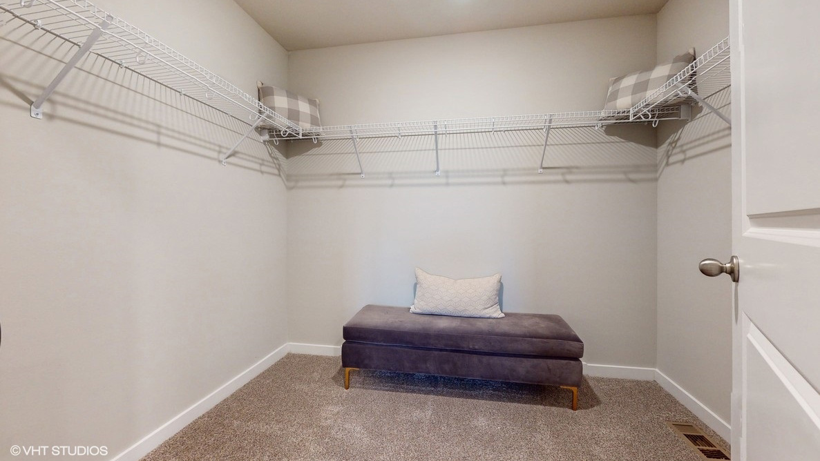 - Large walk-in closet with shelving and ottoman