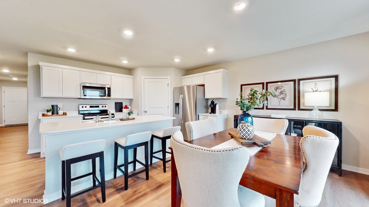 Brown dining room table with white chairs next to kitchen