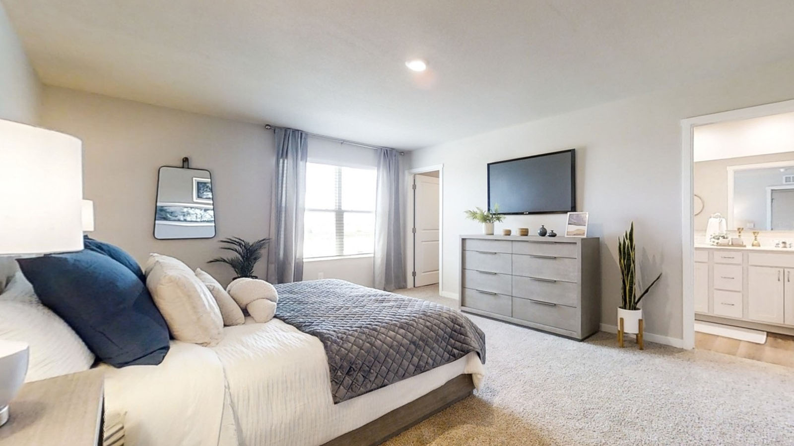 Primary bedroom in the Sydney with a king bed and dresser showing bathroom and closet