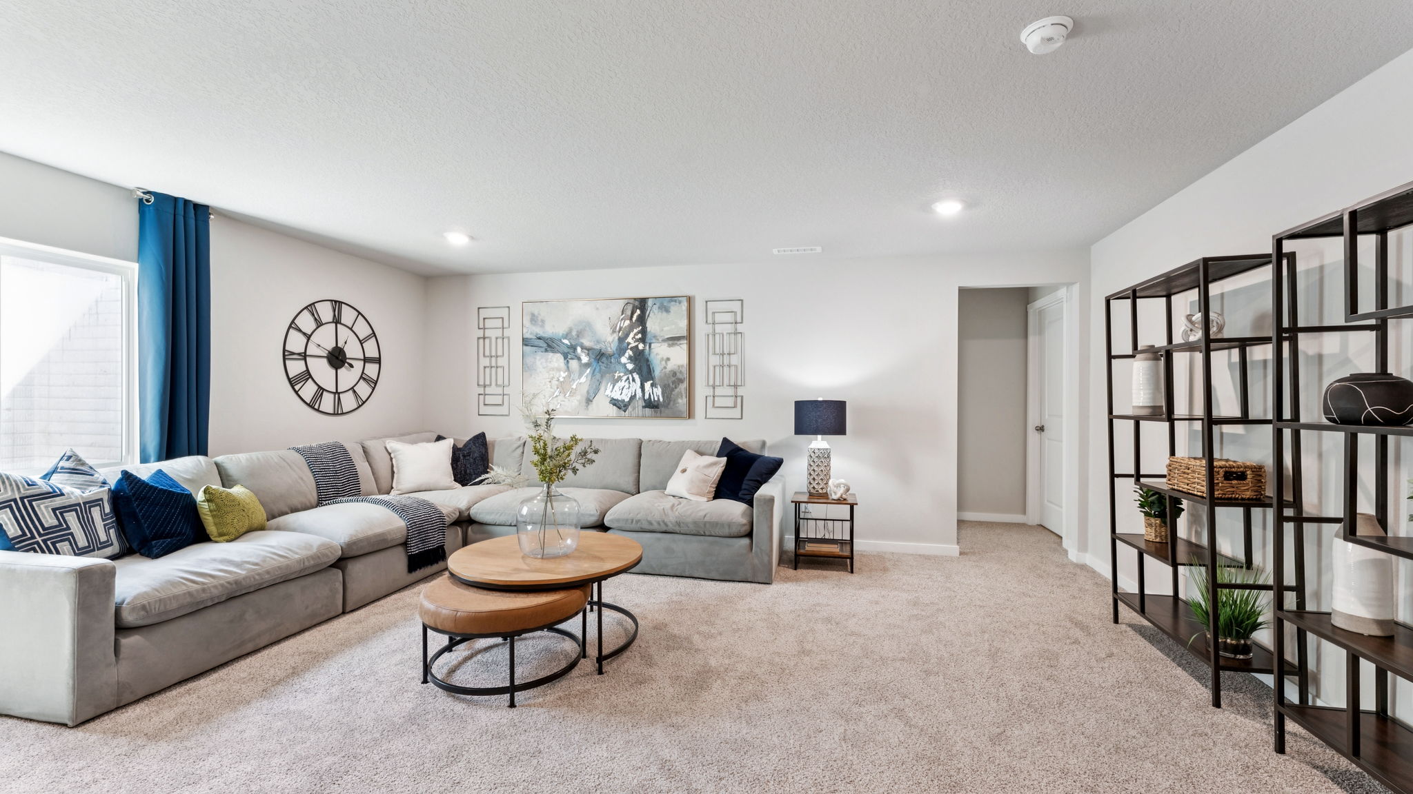 Finished basement family room in the Hamilton with large sectional couch and shelves