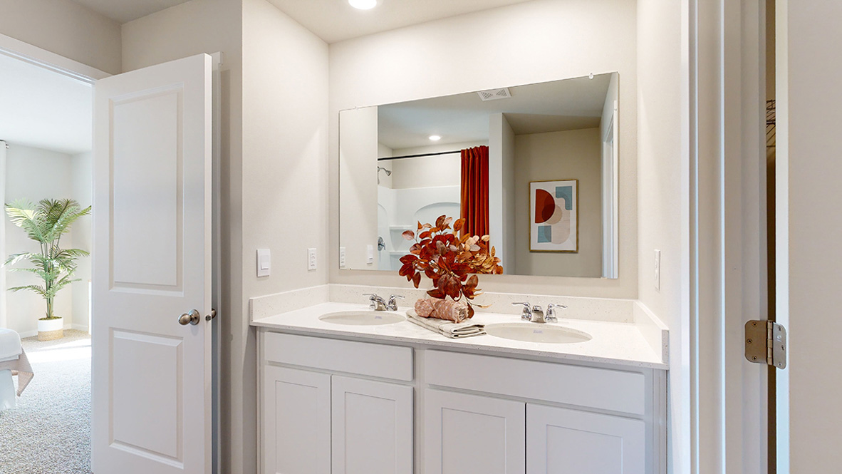 Primary bathroom in the Hamilton with dual sinks looking into the primary bedroom