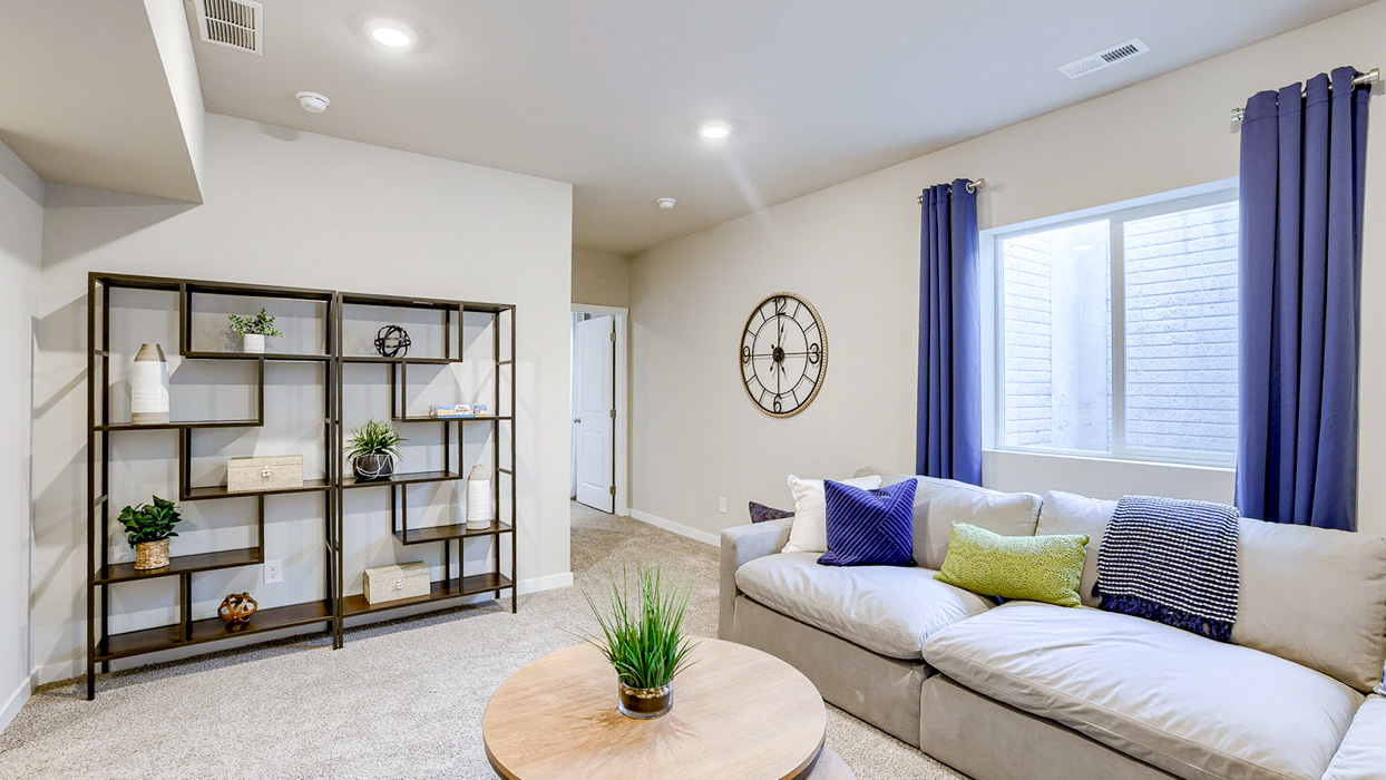 Finished basement in the Bellhaven showing a sectional couch and hallway to the fifth bedroom