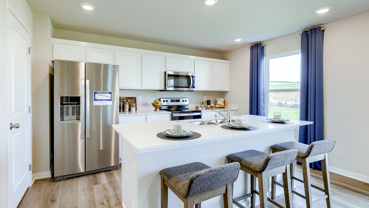 White kitchen wth island and 3 chairs in the Bellhaven