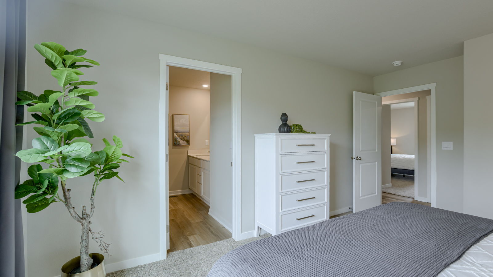 bedroom with beige carpet, beige walls and a window and bathroom door
