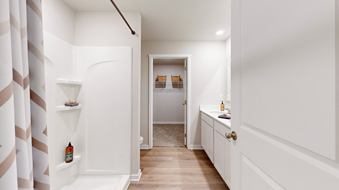 Primary bathroom in the Hamilton with a walk in shower dual sinks and a walk in closet