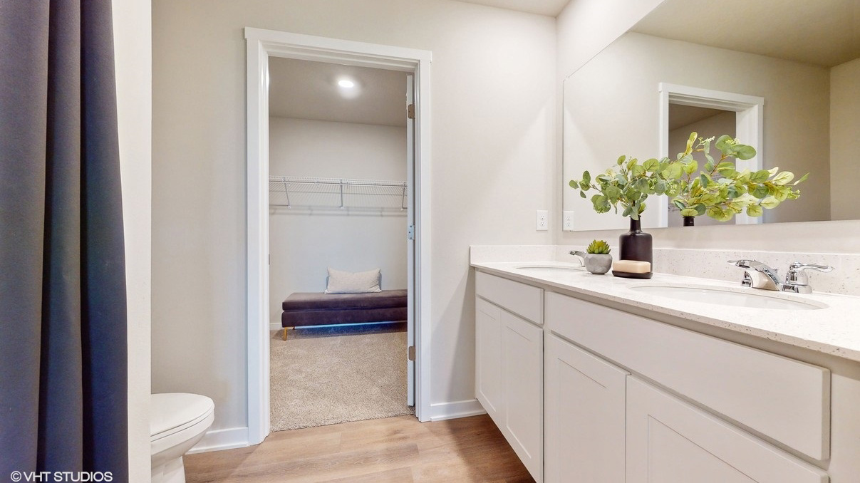 Primary bathroom with white cabinets and walk-in closet