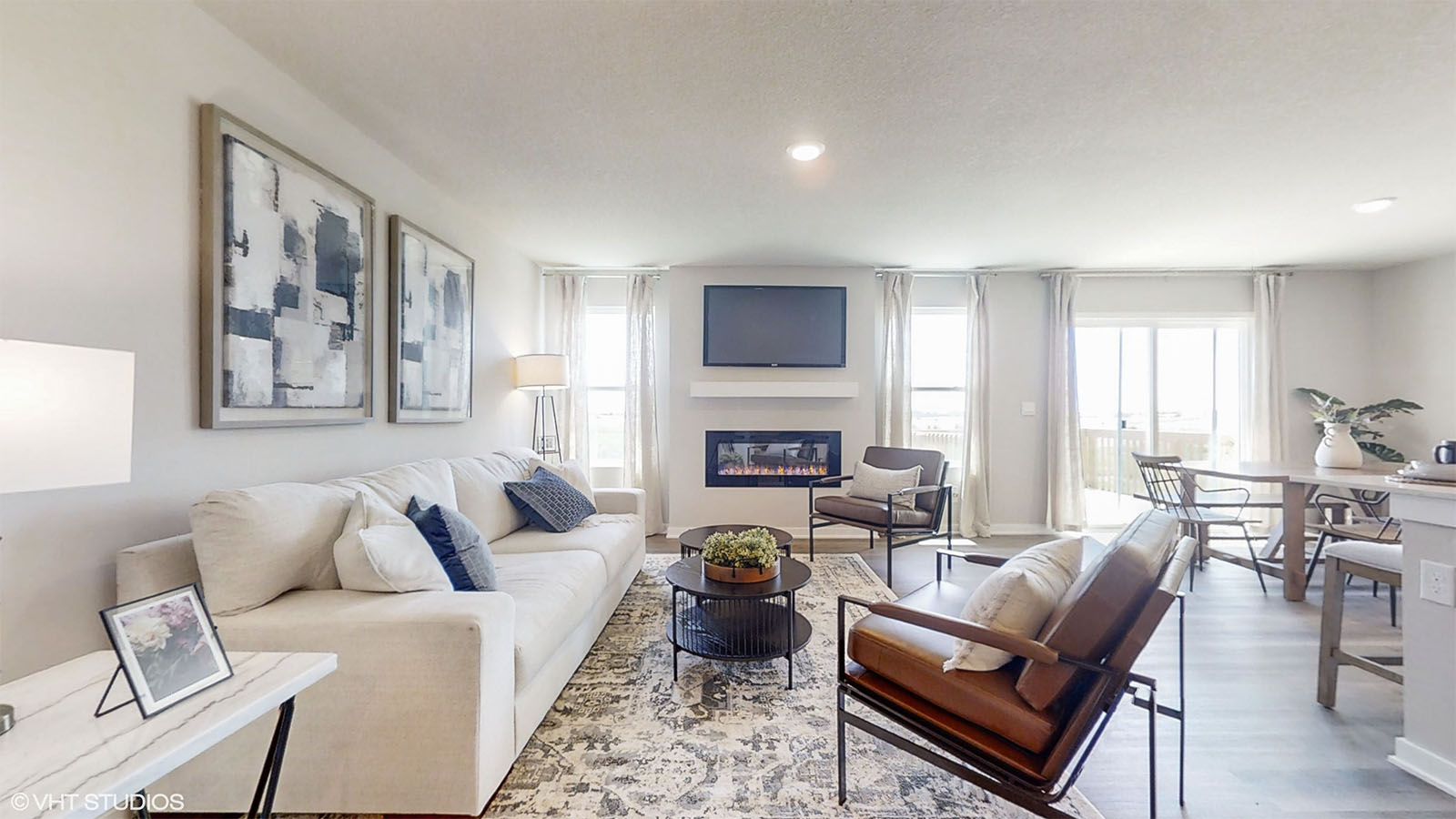 The living room of the Hamilton with a fireplace couch and 2 chairs showing open concept layout