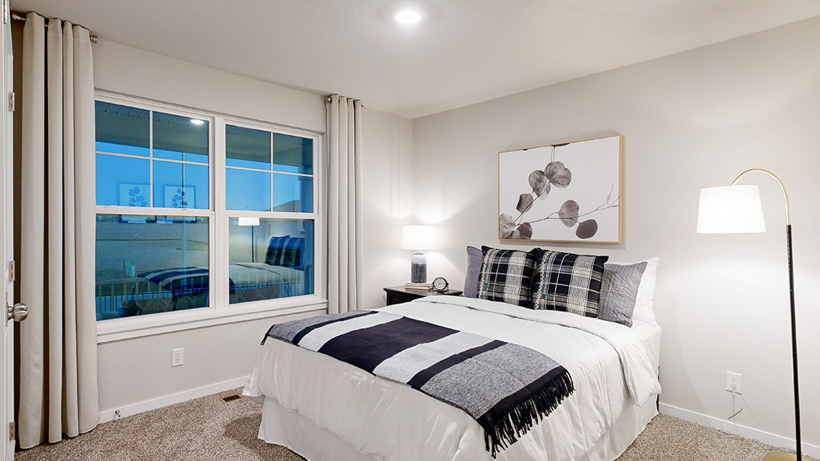 Second bedroom in the Hamilton with a queen bed and lamp