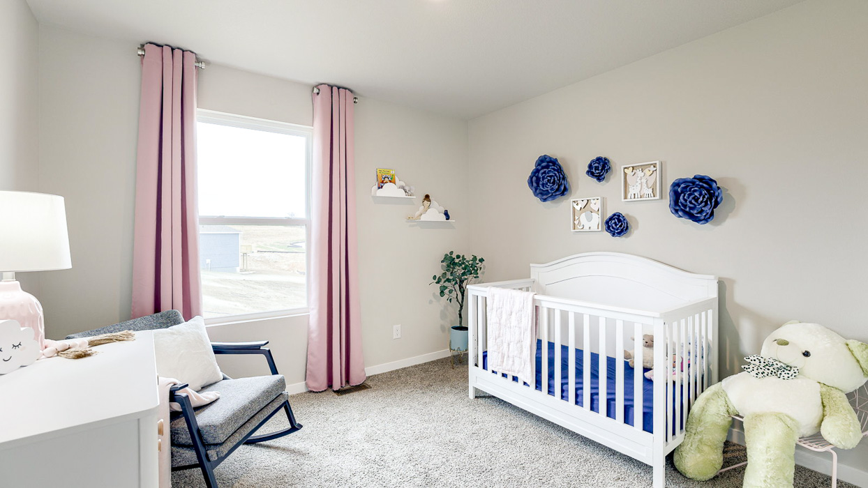 Third bedroom in the Hamilton staged as a nursery with pink curtains