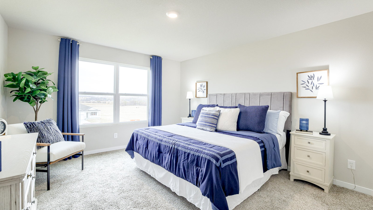 Primary bedroom in the Hamilton with a king bed and chair