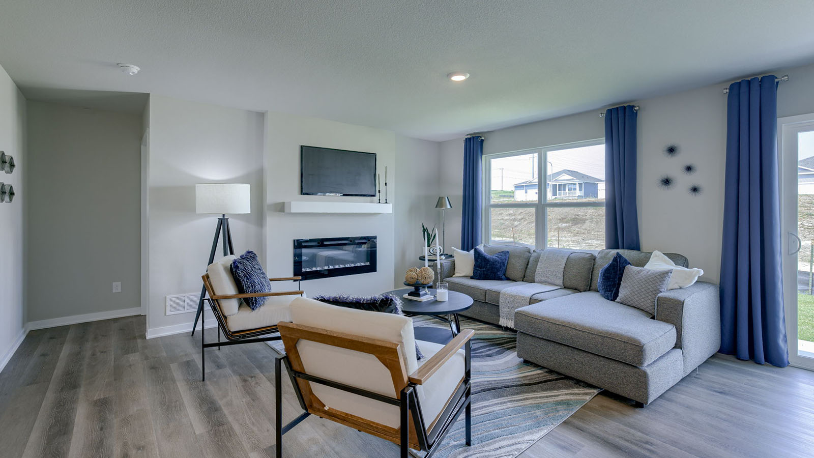 living room of the Roland with a grey sectional and two chairs