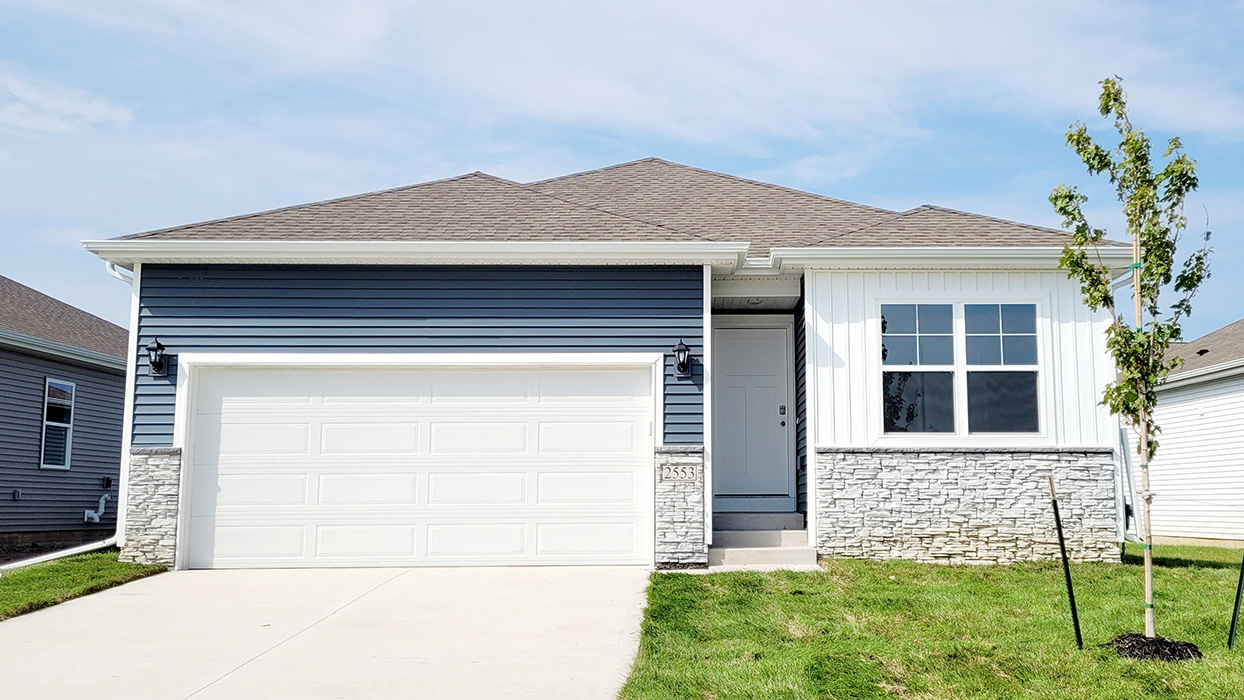 exterior of roland with blue and white siding, stone, and 2 car garage