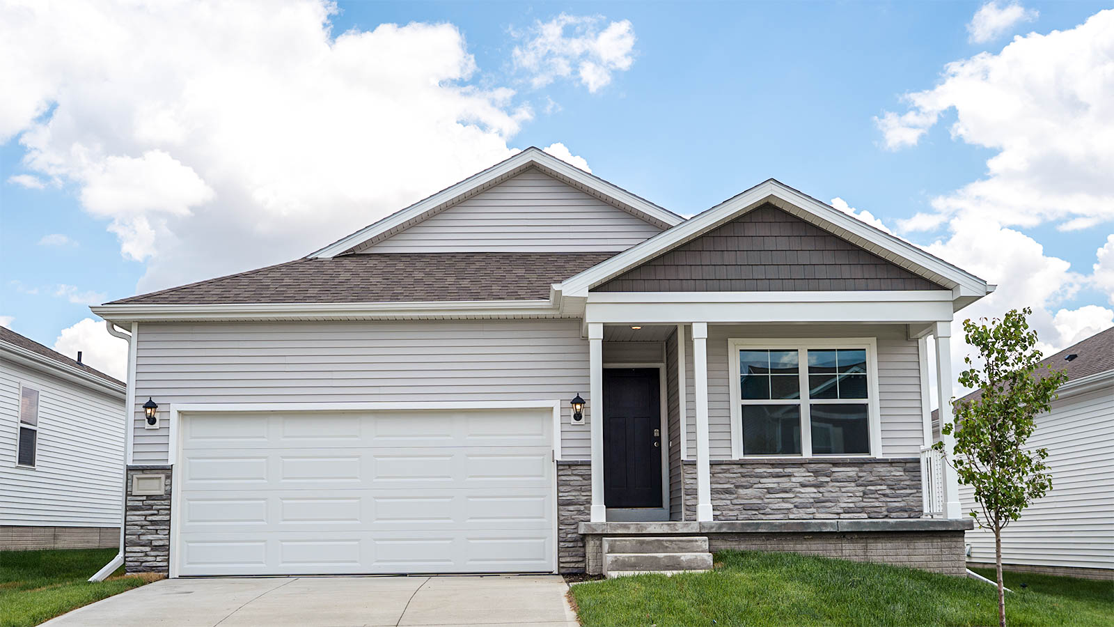 exterior of roland with blue and white siding, stone, and 2 car garage