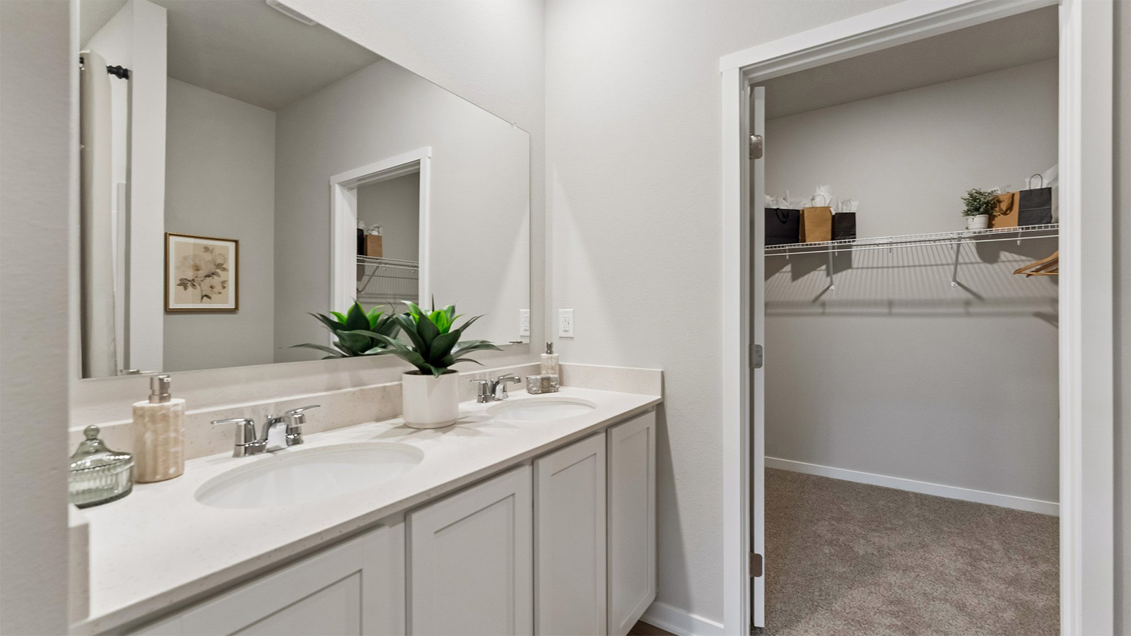 Primary bathroom in the Hamilton with dual sinks looking into the primary walk-in closet