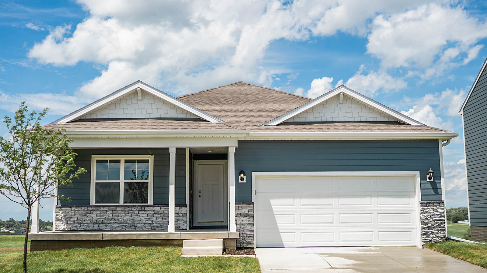 Hamilton Ranch Plan exterior with white siding a two car garage and a spacious front porch