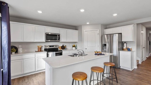 Kitchen of the Holland with white cabinets and island with 3 chairs