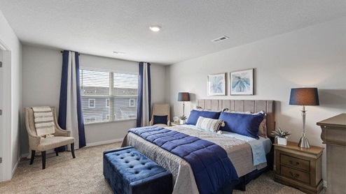 Primary bedroom of the Holland with a king bed and blue footstool and chair