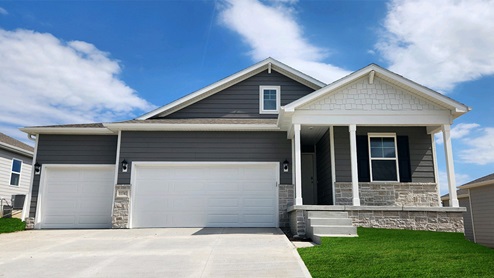 Exterior of the Abbott with blue siding, stone and 3 car garage