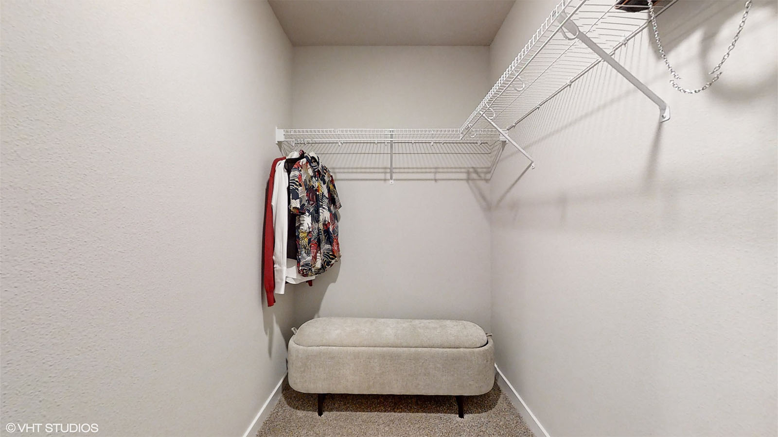 Primary walk-in closet in the Bellhaven with shelving and ottoman