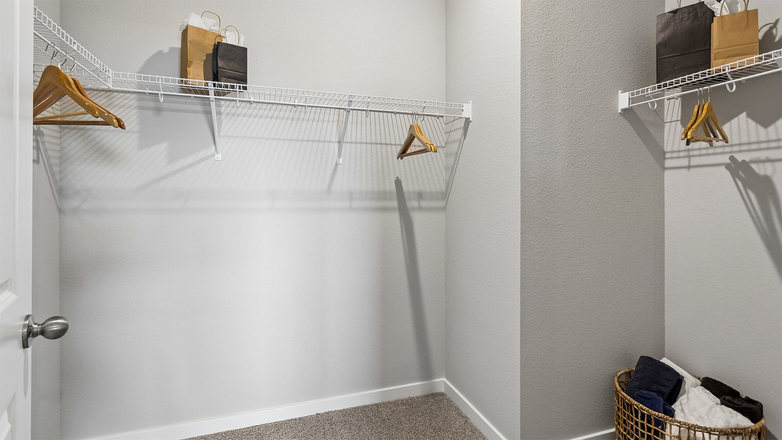 Primary walk-in closet in the Abbott with hangers and shopping bags