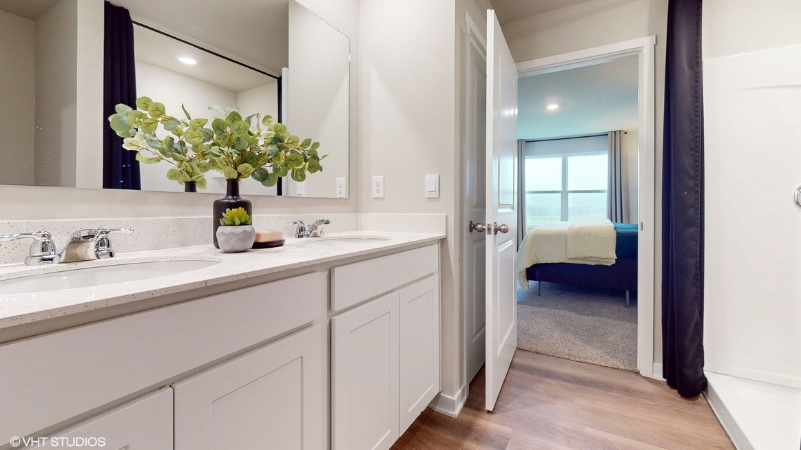 Primary bathroom with large mirror showing bedroom