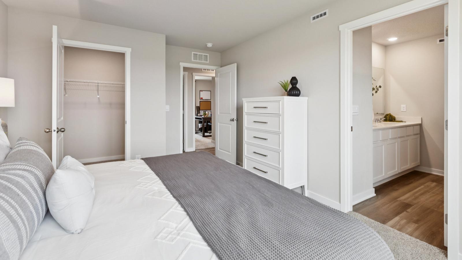 Primary bedroom with carpet, simple furnishings, and a bathroom attached.