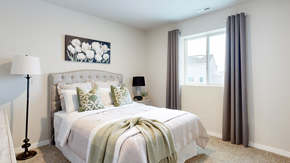 Fourth bedroom in the finished basement of the Reagan with a queen bed and lamp