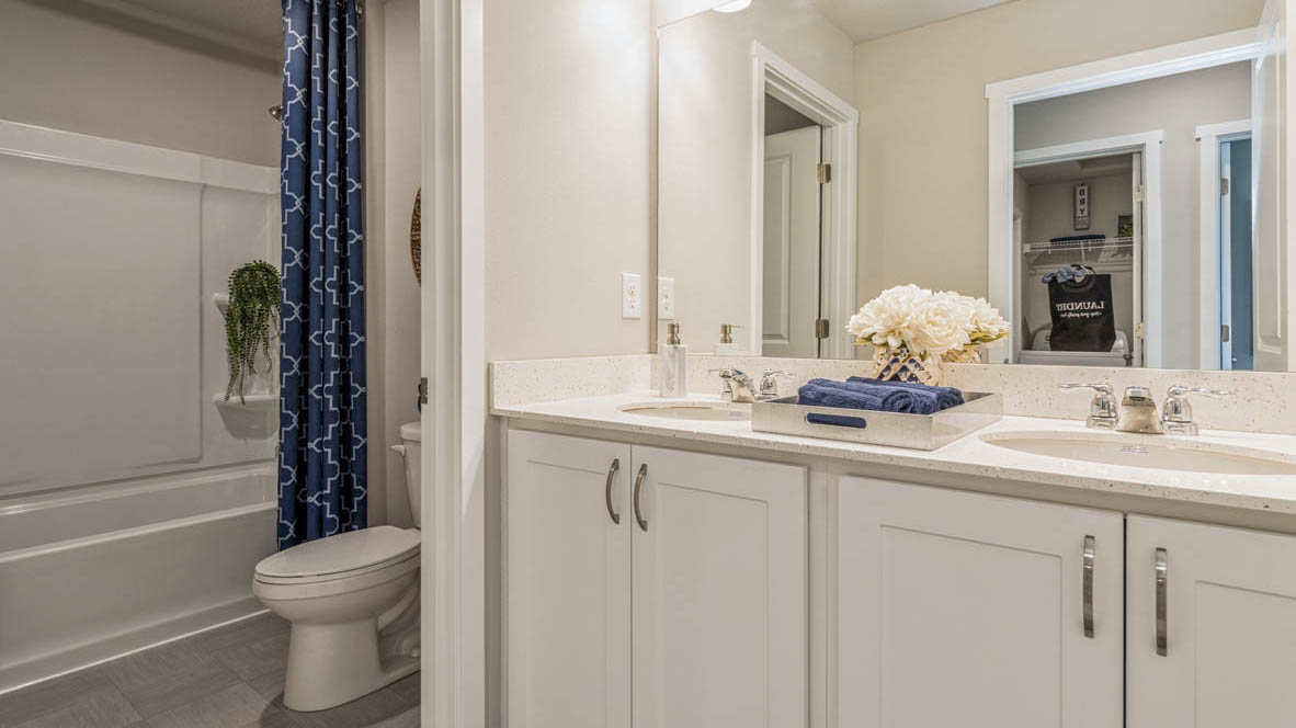 Family full bathroom with stylish vanity, mirror, polished fixtures, cabinets, tub-shower combo in Bridges Mill