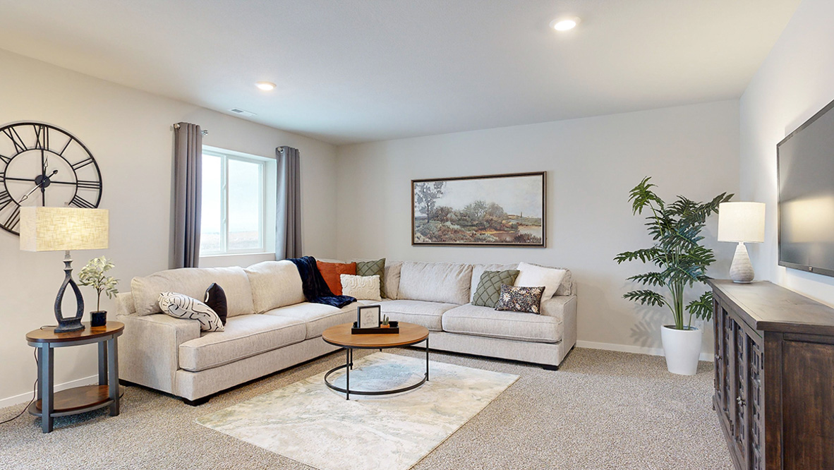 Finished basement living room in the Reagan with a large sectional couch and entertainment area