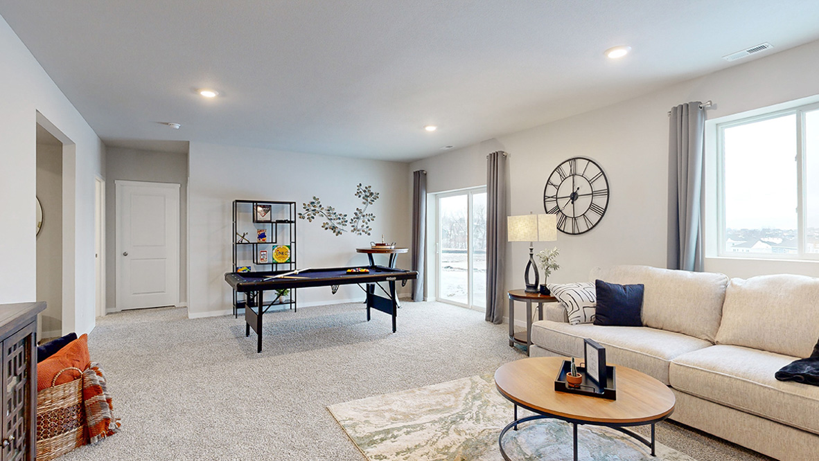 Finished basement living room in the Reagan with a sectional couch and pool table