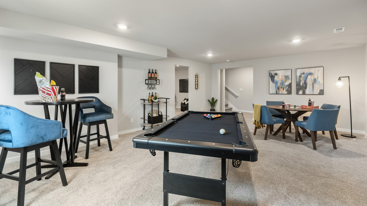 Finished basement with pool table and chairs