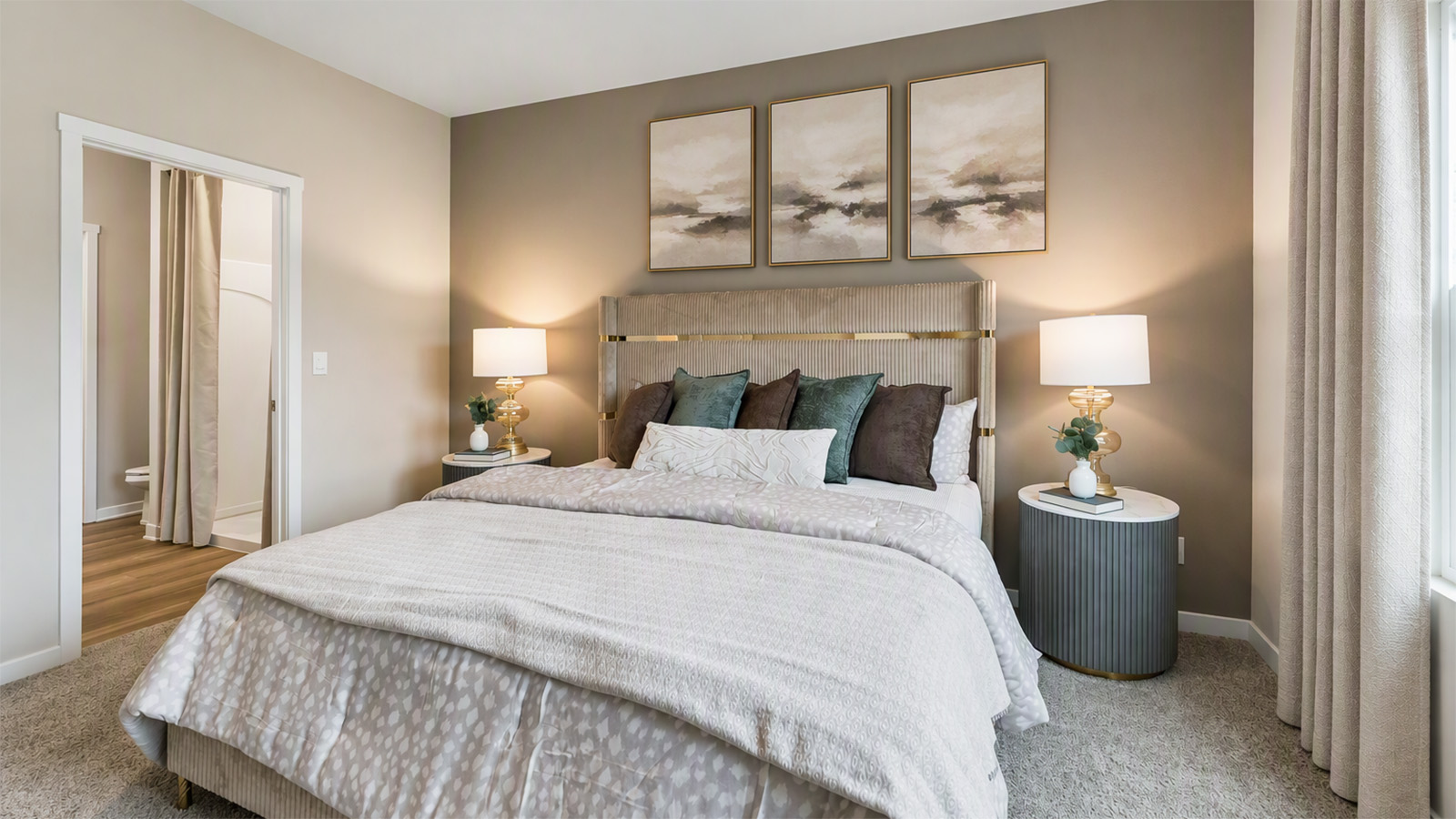 Primary bedroom in the Hamilton with tan accent wall looking into the primary bathroom