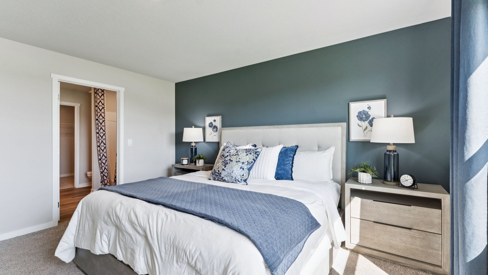 Primary bedroom in the Hamilton with king bed and accent wall looking into the primary bathroom