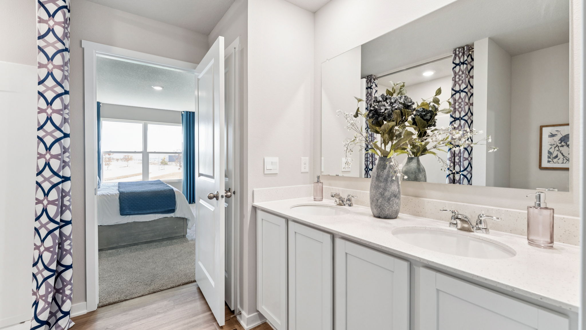 Primary bathroom in the Hamilton with dual sinks and walk-in shower looking into the bedroom