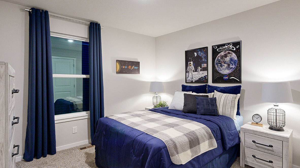 Third bedroom in the Hamilton with a full bed and navy curtains