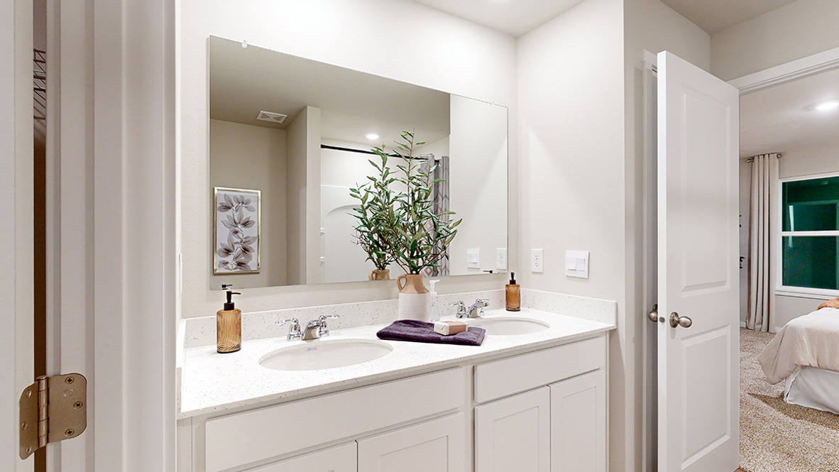 Primary bathroom with dual sinks looking into the primary bedroom in the Hamilton