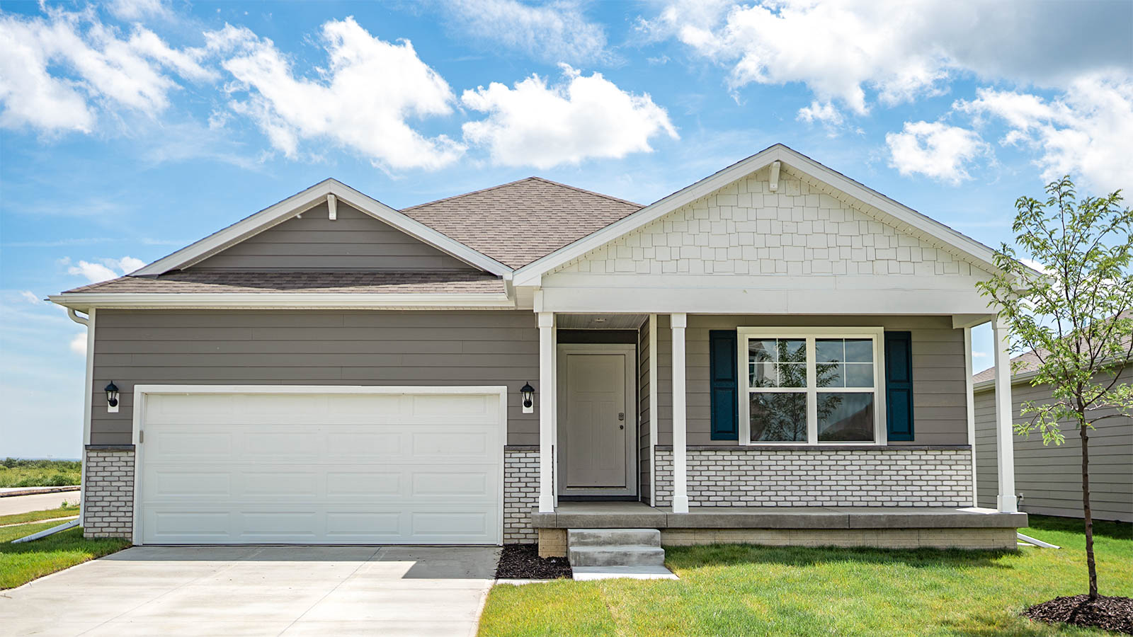 Exterior of Neuville, 2 car garage, covered front porch, wtith tan siding.