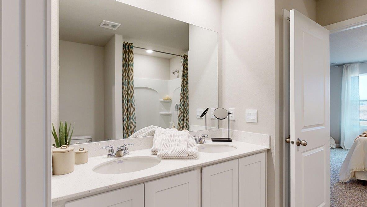 primary bathroom with dual sinks and white cabinets