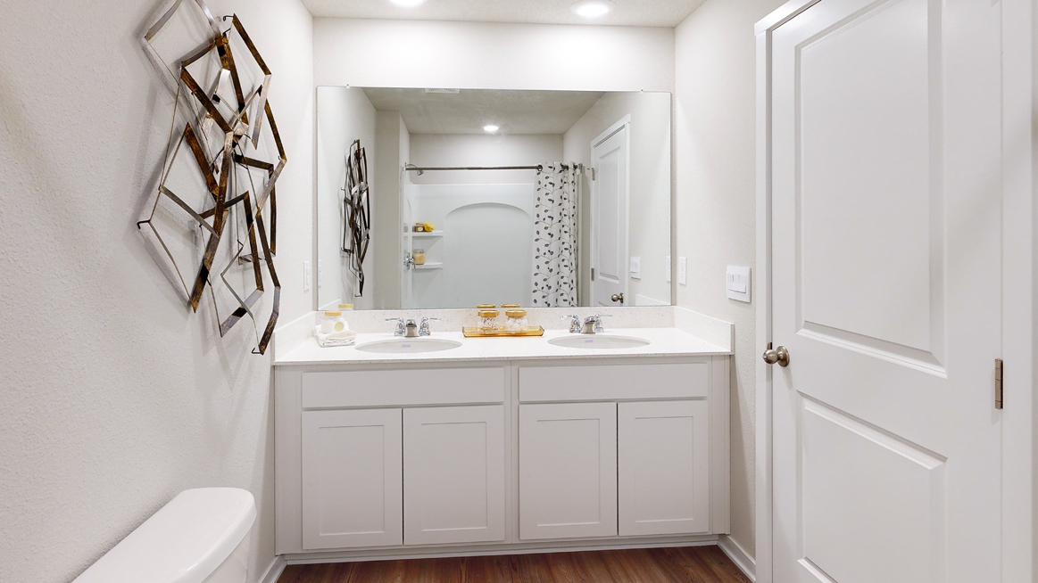 Primary bathroom in the Freeport with a dual sink and white cabinets