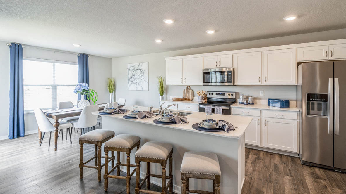 Open concept kitchen with island and 4 stools overlooking the dining area in the Emerson