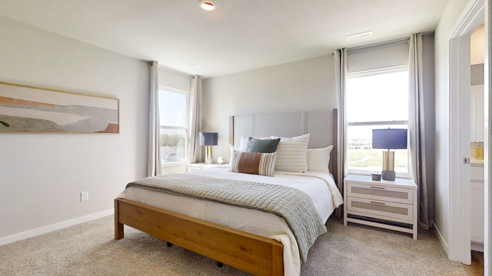 Primary bedroom in the Emerson showing king bed and natural lighting from 2 large windows