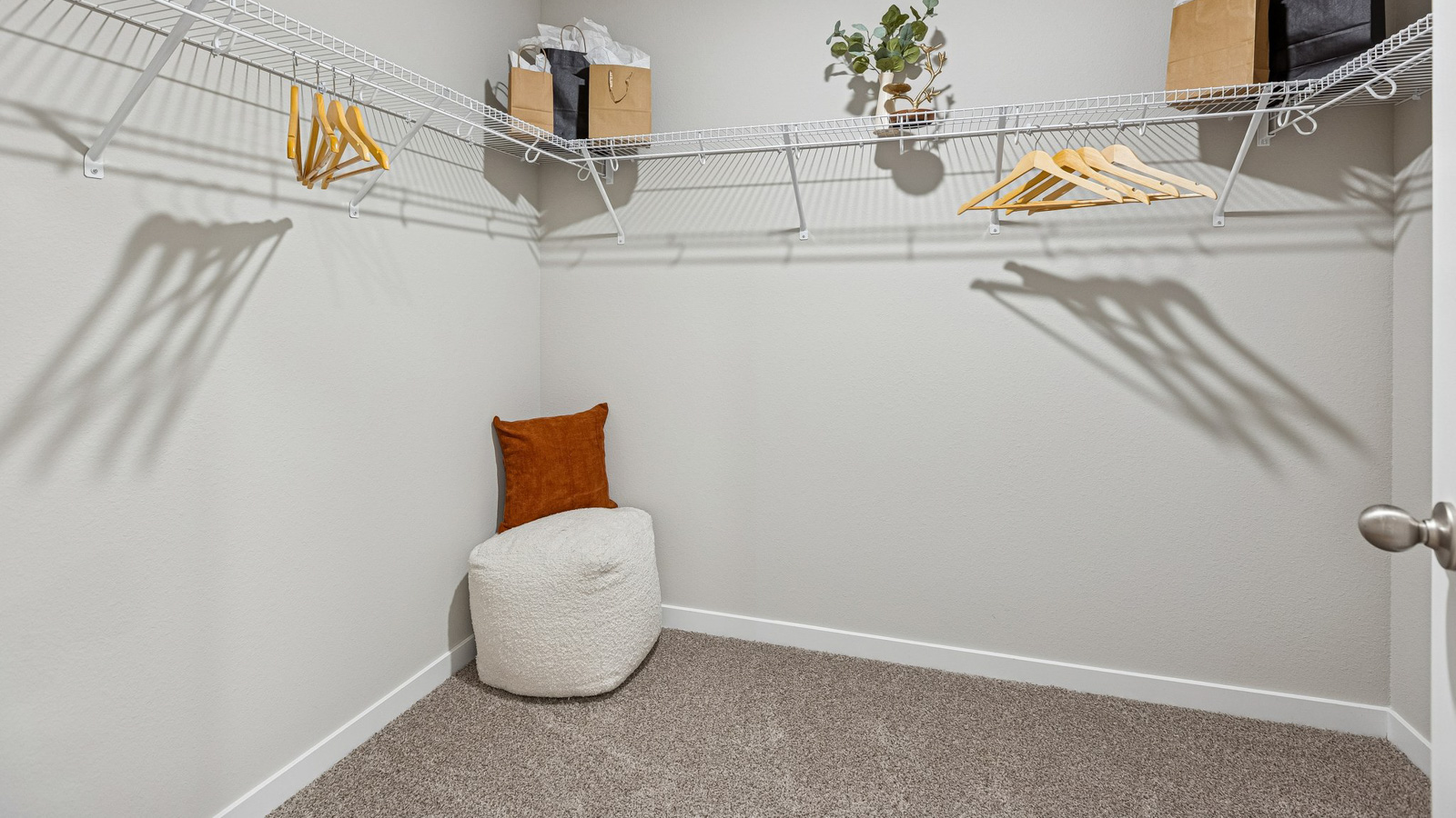 Hamilton primary walk-in closet with small ottoman