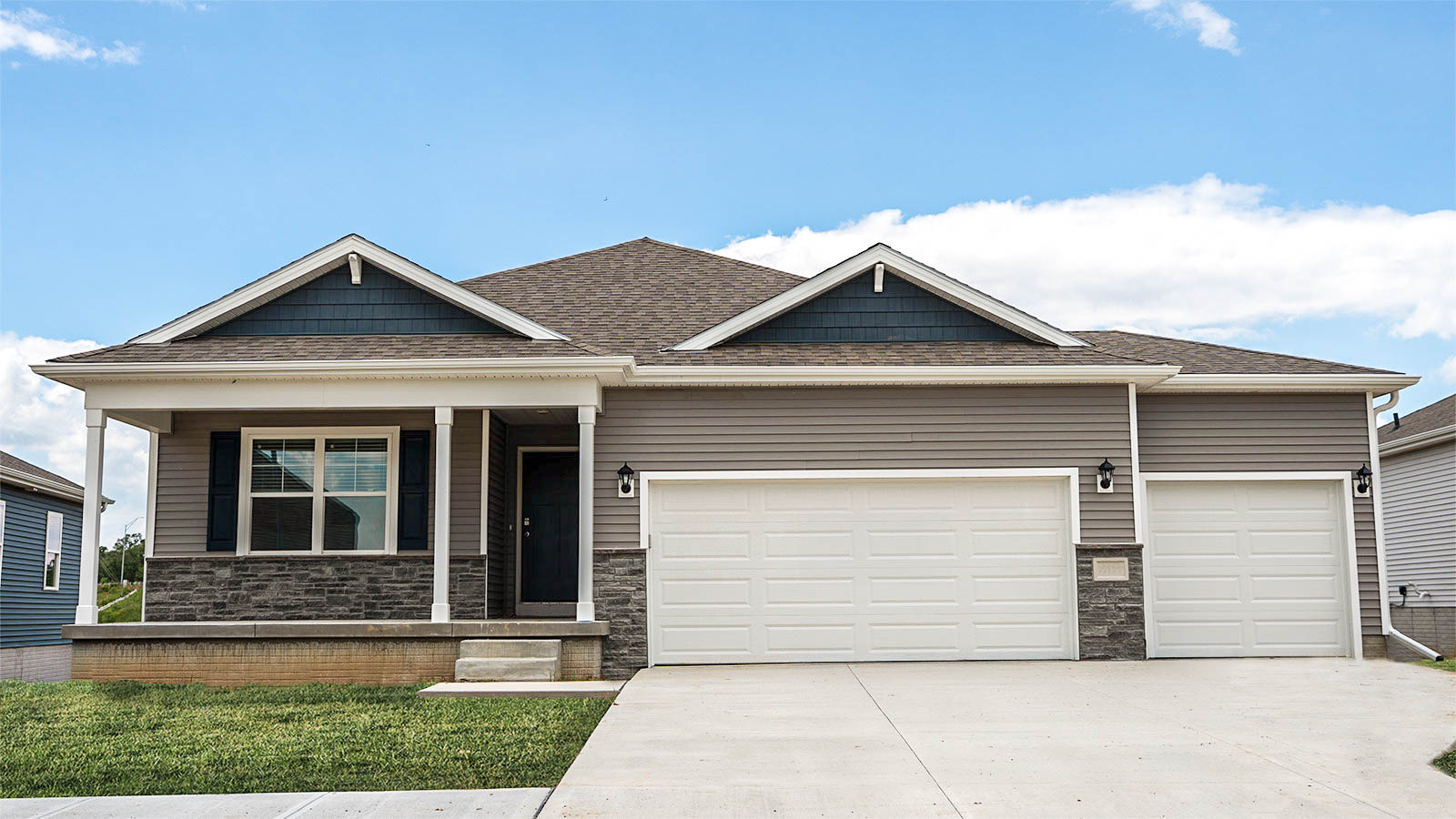 Exterior of The Hamilton Floorplan with a three car garage and covered front porch with brown siding