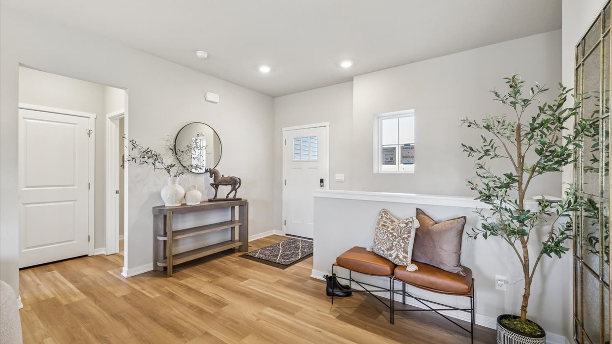Welcoming entry foyer with wood-look flooring, decorative console table, bench seating, and contemporary accents.