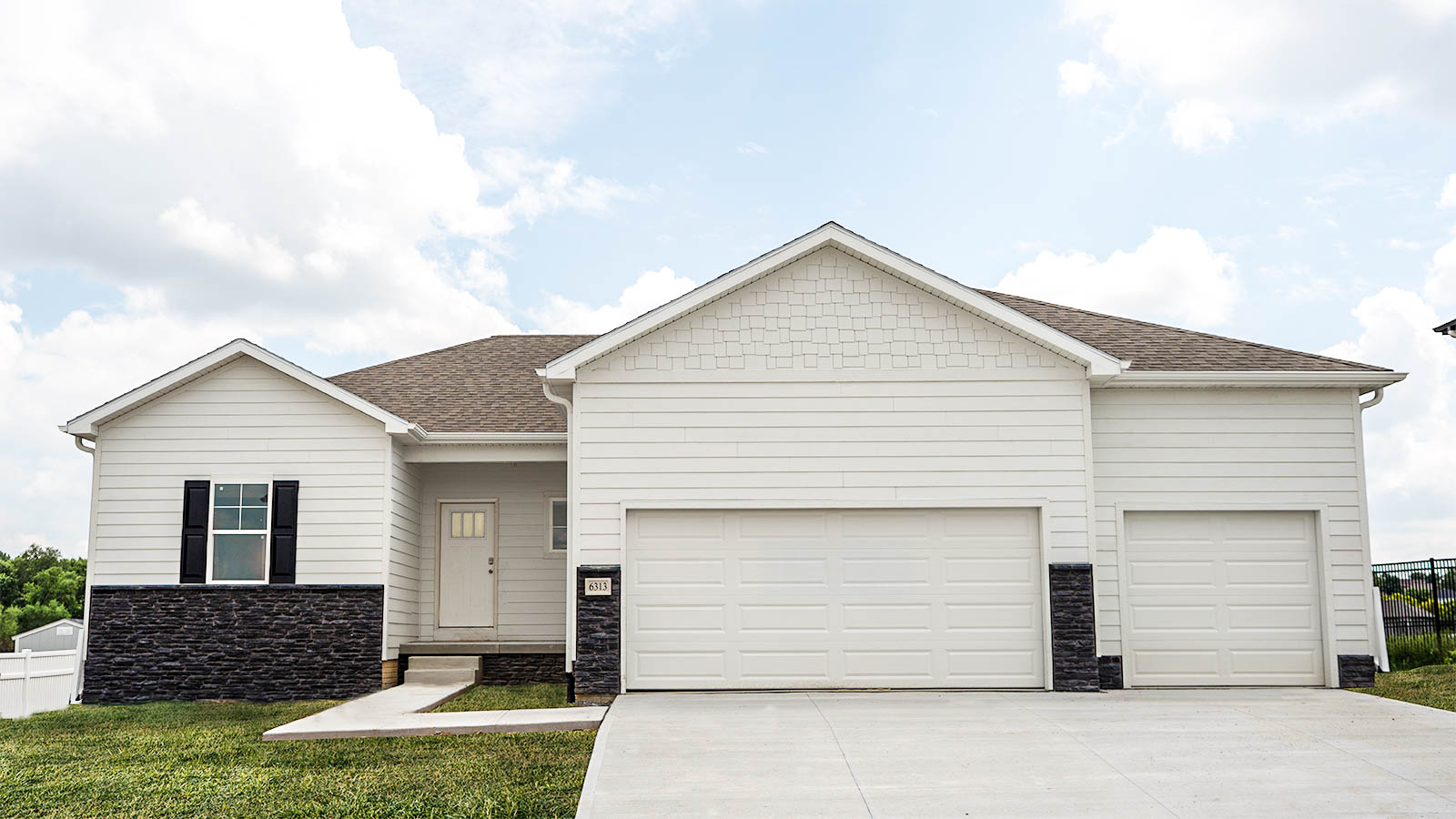 Reagan exterior with white siding, black stone, and a 3 car garage