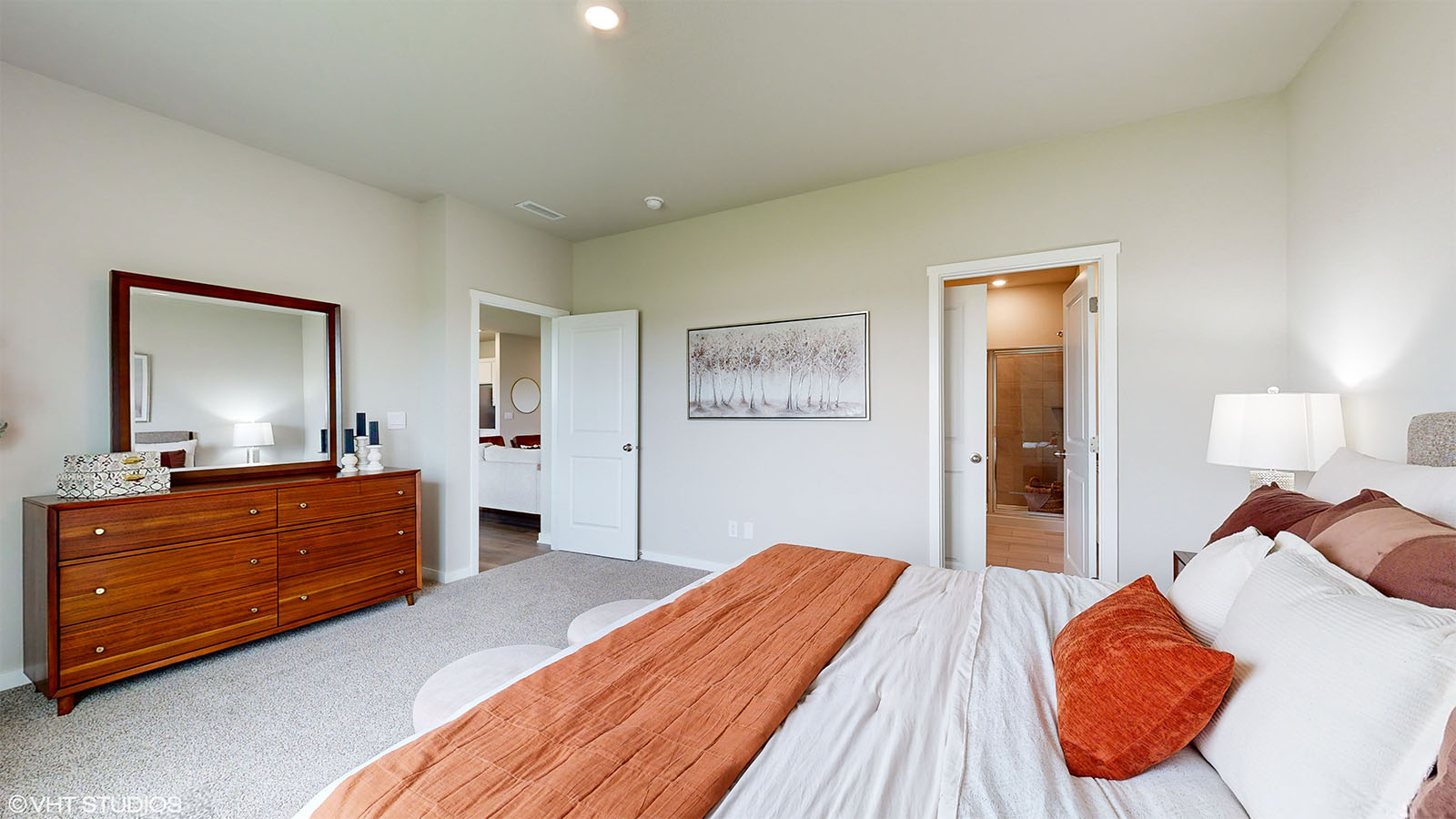 Primary bedroom in the Fairfield with a king bed and dresser looking into the primary bathroom
