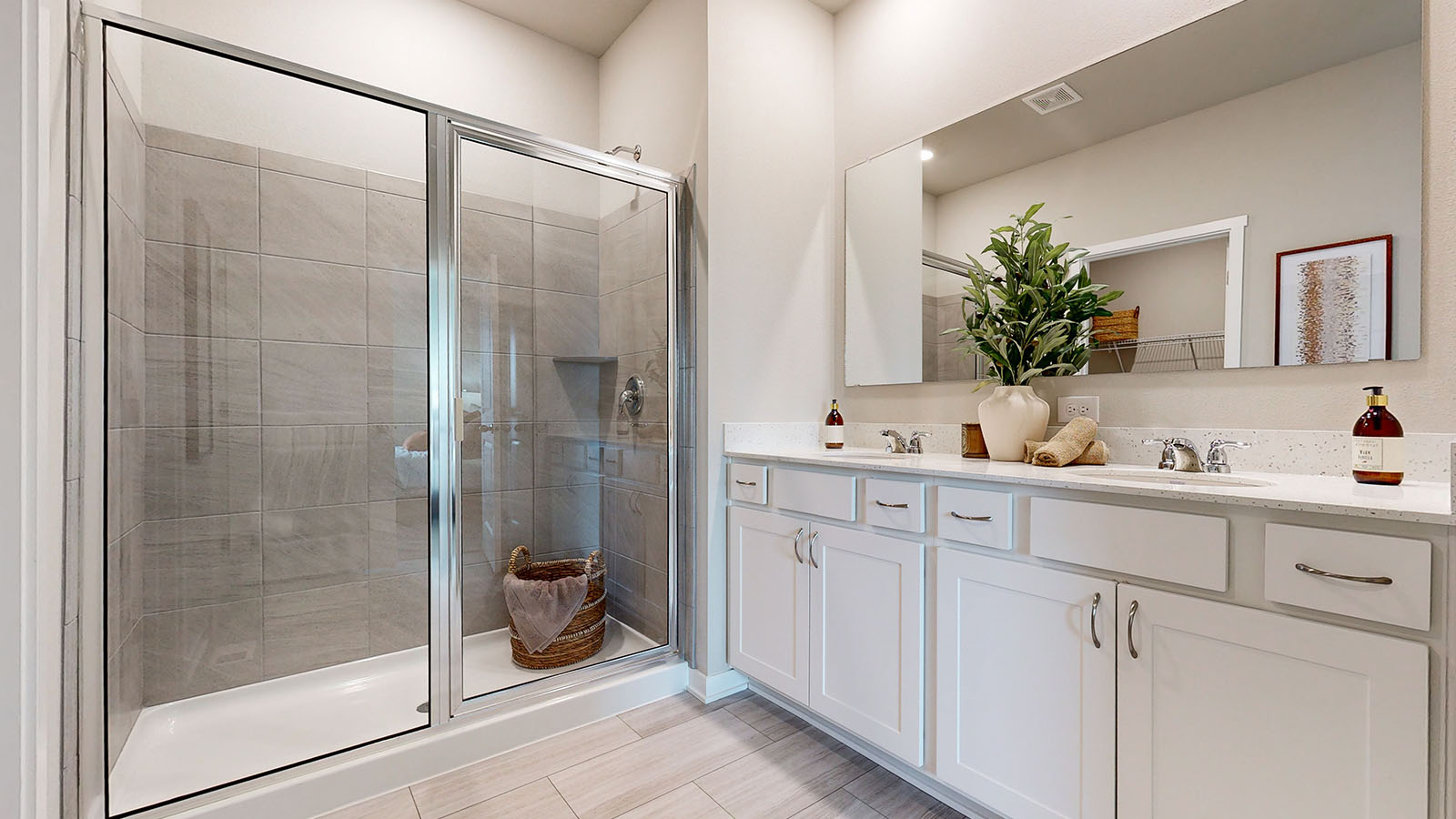 Bright primary bathroom of the Fairfield with a walk-in glass door shower and dual sinks