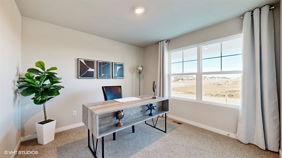 Second bedroom in the Neuville staged as a home office with a desk and chairs