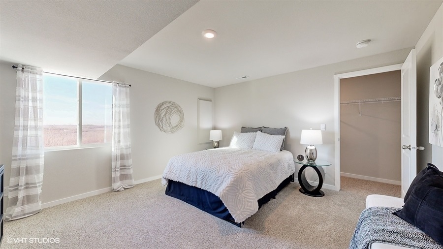 Fourth bedroom in the finished basement of the Neuville with a full bed and large window